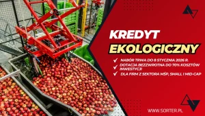 Maszyna sortuje czerwone jabłka na przenośniku taśmowym w fabryce. Obok czerwony baner reklamuje przyjazną dla środowiska pożyczkę dla małych i średnich firm, wspominając o dotacjach do 70% kosztów inwestycji i terminie do 8 stycznia 2026 roku.